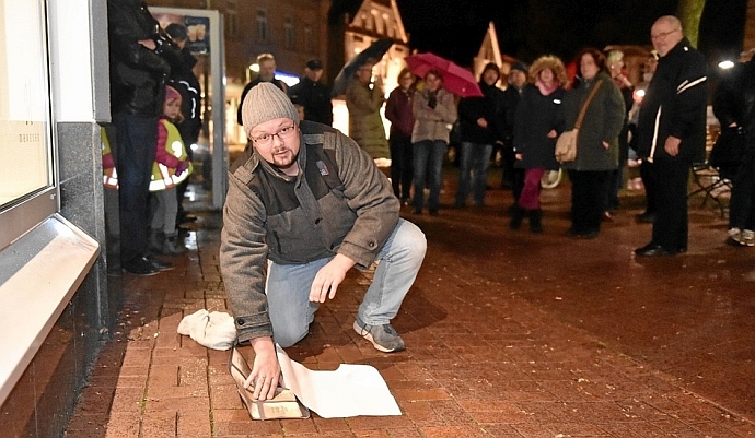 Sebastian Rolf bringt am Unteren Markt eine Folie auf, die einen Eindruck von den Stolpersteinen vermittelt. Die sollen im kommenden Frühjahr an vier Stellen in Ibbenbüren gesetzt werden.